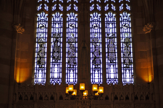 Dramatically backlit medieval figures depicted in Sterling Memorial Library's stained glass windows
